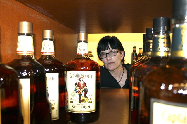 North Bend Liquor Store employee Lori Laughren straightens bottles of rum on Wednesday