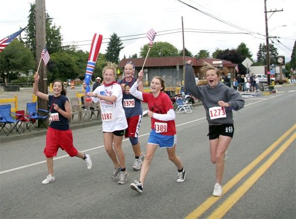 Flag-waving runners come down Tolt Avenue during the Run for Pies