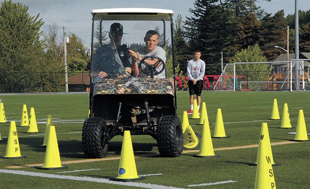 Hank Van Liew crushes cones as he tests behind the wheel of a golf cart in the 'Think and Drive' assembly at Mount Si High School. Highway patrolman J.P. McAuliffe is along for the ride.