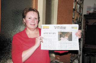 Tina McCollum of North Bend displays her image on the Gangjin Times. McCollum