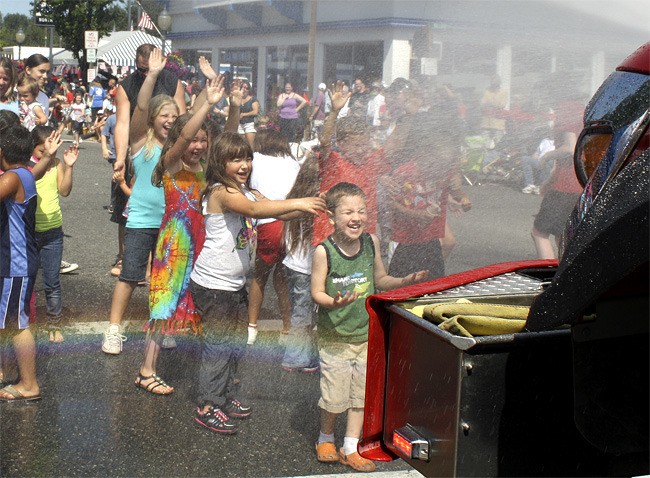 Young people frolic in the rainbow-tinted spray from a North Bend fire truck at the close of the Festival at Mount Si grand parade