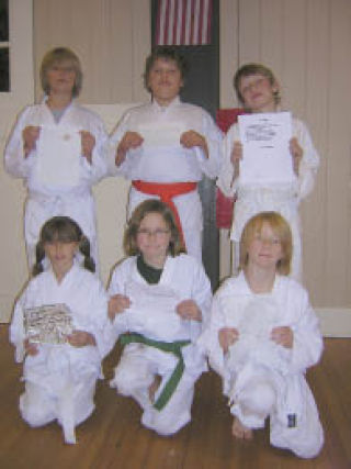 Proudly displaying their Halloween poems are karate students (back row
