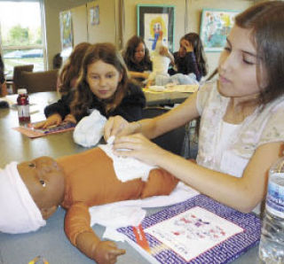 Kaitie Gallagher of Snoqualmie practices diapering a baby doll while Rachel Massey of North Bend looks on