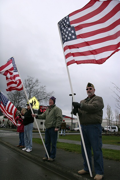 Mount Si Lutheran Church members Bob Bartlett and Harvey Oster raise flags at the entrance to Mount Si High School on Saturday