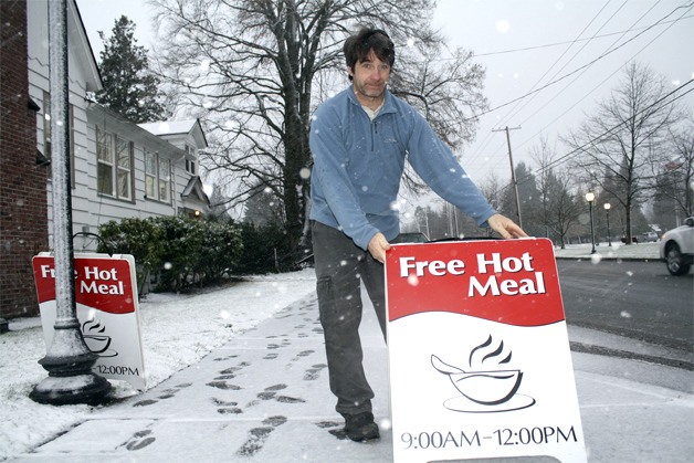 Braving the snow to place signs announcing a warm weekly meal
