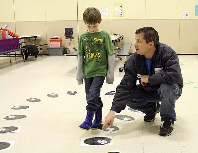Josh Matson shows his son Aiden the next word along the sight-reading path during a Dec. 8 parent-child reading workshop hosted by the Snoqualmie Valley School District Dec. 8 at Opstad Elementary School. Reading workshops will be offered at all elementary schools again in May.