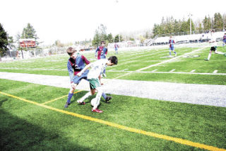 Visiting player Robbie Kerr of Bishop Heber High School battles for a ball against a Cascade FC defender during play Saturday