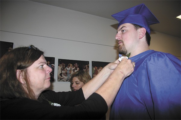 Two Rivers grad Sean Stone gets help with his gown prior to the ceremony.
