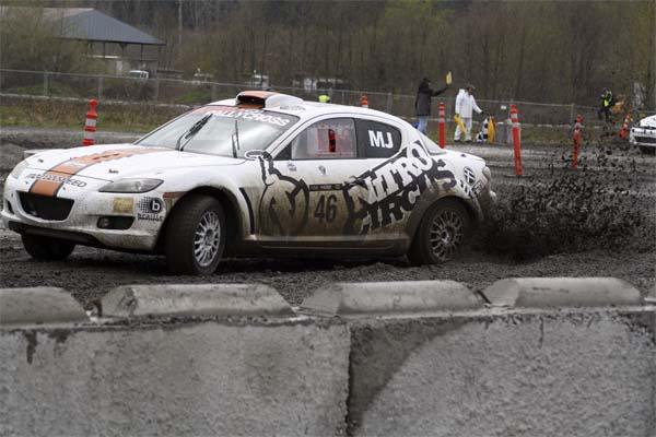 A rally car slops through a muddy turn at the finish line of the Global RallyCross heat Friday afternoon