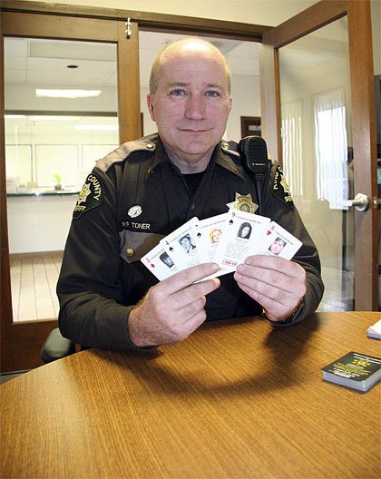 North Bend Police Chief Mark Toner holds five playing cards depicting unsolved homicide cases in the Snoqualmie Valley. The pack of cards