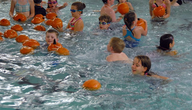 Children swim with a flotilla of floating pumpkins at the 2014 Si View Pool pumpkin patch.