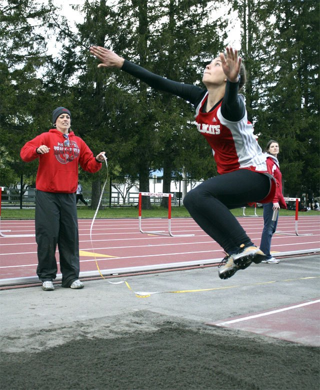 Coach Megan Botulinski watches as Mount Si’s Sarah Miller reaches the apex of her triple jump. Miller tied with teammate Sophie Rockow for first in Thursday’s Interlake meet.