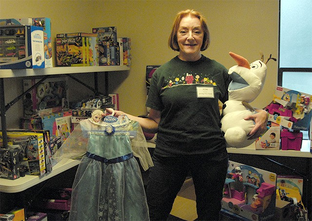 Event helper Kim Irvine holds some of the year’s most popular toys—anything to do with the movie “Frozen”—from the storage room for OneVOICE donations
