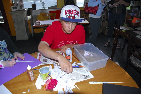 Christian Holt picks out another paper strip to transform into a jewelry bead during the Bead for Life fundraiser Thursday. Holt and his Current Events class at Two Rivers School hosted the fundraiser