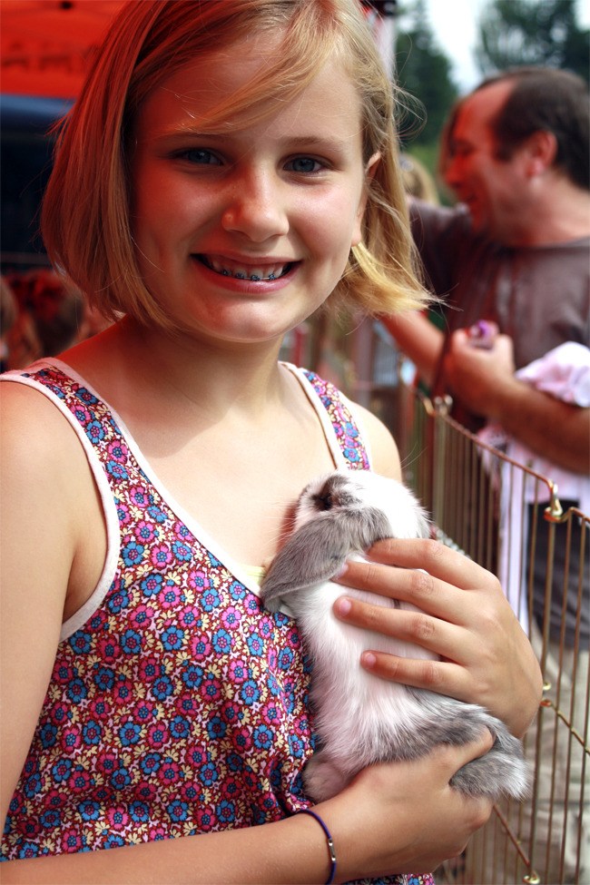 A Block Party-goer at last year’s Animal Encounters petting zoo cradles a young rabbit; The Encounters team uses special ‘bunny boat’ holders to make sure the animals feel safe.
