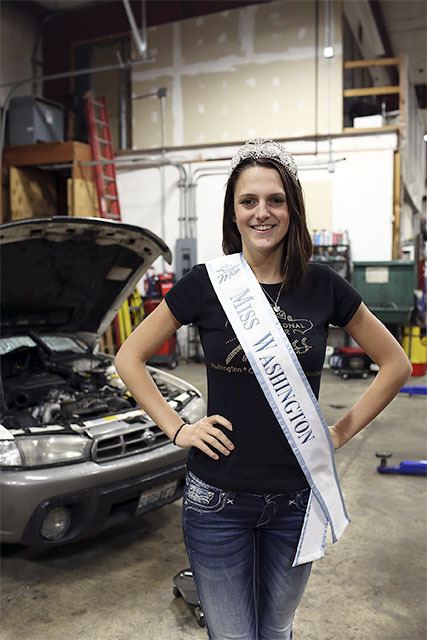 HayleeMae Dennis poses with her International Junior Miss Washington crown and sash at her mom’s auto repair shop