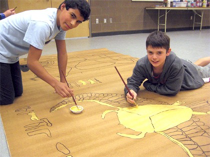 Sixth graders Christian Tomlinson and Jake Karavais paint a Egyptian scarab gold for the wall art that will cover TFMS common walls to give it a Egyptian tomb feel.