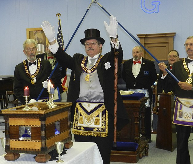 Grand Master Bruce Vesper reactivates North Bend’s Unity Masonic Lodge for another century of service to the community. Grand Lodge deacons Fred Moser and Cary Cope hold the ceremonial staffs behind him
