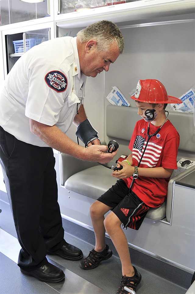 Carnation boy Tim Bennett takes Fire Chief Lee Soptich’s blood pressure at the 2015 Carnation Fourth of July celebration