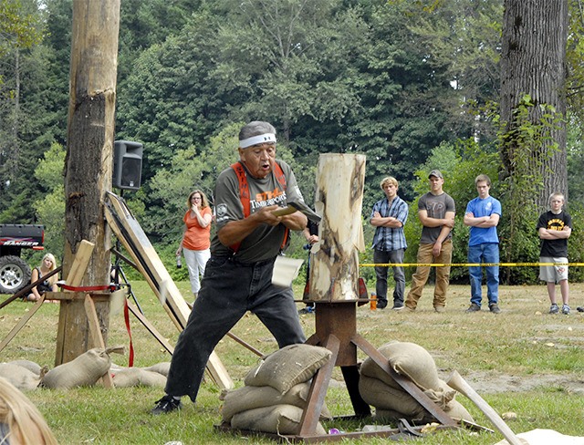 David Moses Sr. races to cut through a log in a timber sports demonstration.