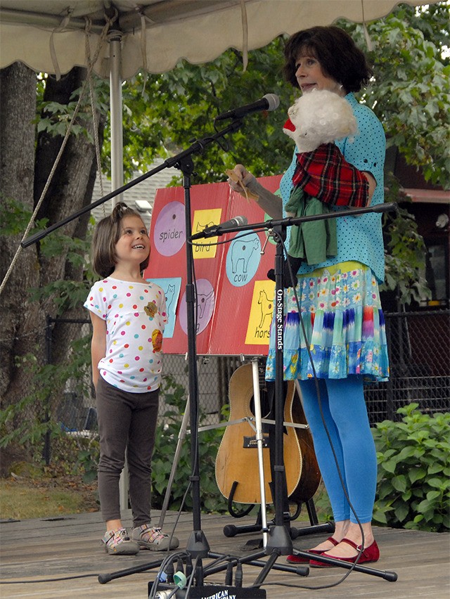 An audience volunteer helps performer Nancy Stewart with a song at the Kids' Stage.