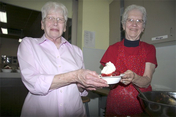 Volunteers Shirley Hammerquist and Delores Ulrich serve up a strawberry shortcake with all the fixings at Sno Valley Senior Center during the community Fourth of July party.