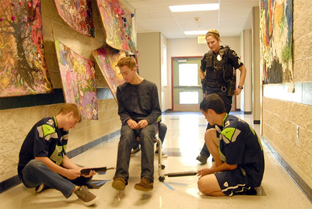 Cedarcrest High School Resource Officer Lori Batiot stops to watch a science class conduct a hallway experiment. Mitchell Frimodt