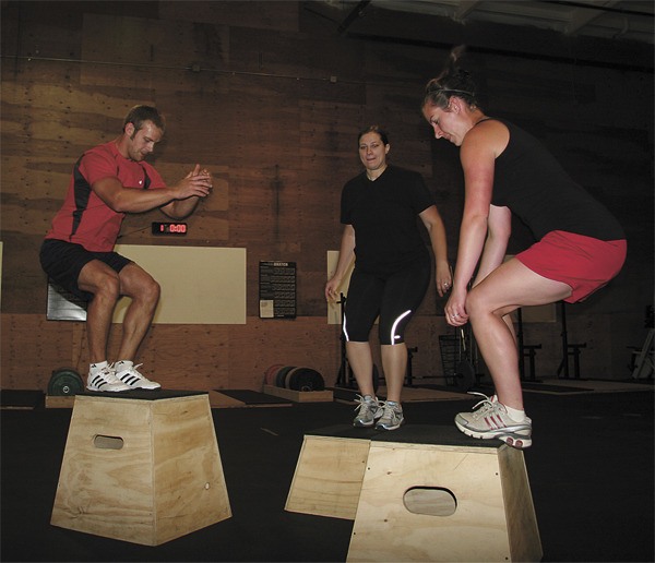 Kyle Jacobsen leads North Bend residents Cheryl Roy and Sarah Mellon in a box jump exercise at Cascade Crossfit gym