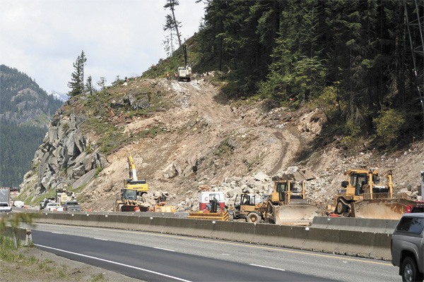 Construction crews working for the Washington Department of Transportation clear debris on a rock face overlooking Interstate 90 on Snoqualmie Pass. Blasting means evening delays on the route this summer.