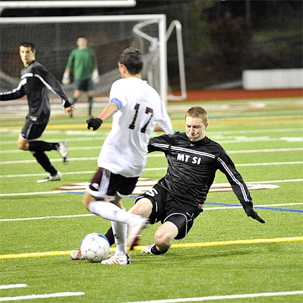 Wildcat Ben Larson slides to the ground in an attempt to get ball away from a Mercer Island offensive player Tuesday.