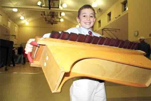 Second grader John Bosworth hauls a vibraphone to the school music room following a class concert Thursday