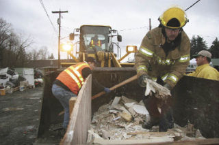 City employees Mike Roy and Bill Dalman and firefighter Ron Payne work to unload sodden drywall from a trailer at the city of Snoqualmie disposal site on Sunday
