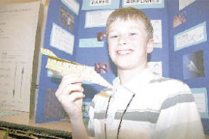 Cascade View Elementary School student Reid Lutz shows off the classic form of the paper airplane. He and teammates explored which paper airplane would fly best  the original