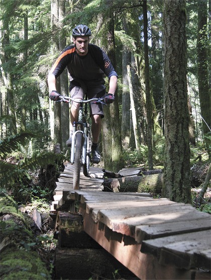 Cross-country cyclist Isaac Pattis explores a log bridge feature in Fall City-area Duthie Hill Mountain Bike Park. The rider-created park officially opens on May 22.