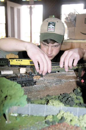 Northwest Railway Museum volunteer Isaac Farrar carefully settles a model train car onto its tracks on a new museum diorama. Volunteers including Farrar spent hundreds of hours creating the mock-up of the future campus