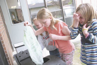 Chloe King reacts to the stench of Snoqualmie Elementary’s worm bin as Sadie Woolf dumps food scraps into it for composting. Along with Amanda Antoch