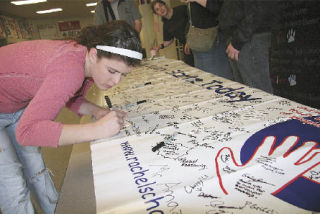 Signing her name on a giant banner