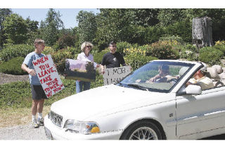 North Bend residents Rob Salopek and Peggy and Tom Bindus explain to curious passersby why they’re protesting outside of T-Mobile’s July 11 company picnic