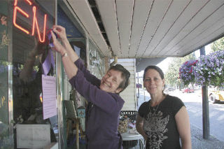 Wendy Thomas and Cris Coffing put up a purple ribbon on the door of Isadora’s Books and Cafe on Monday morning