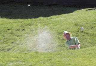 Knocking the ball out of a sand bunker on the 18th hole during the first day of the tournament