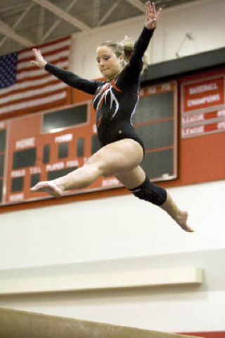Brittay Cragin catches air on the beam during competition at home last week during senior night. “We really came together as a team