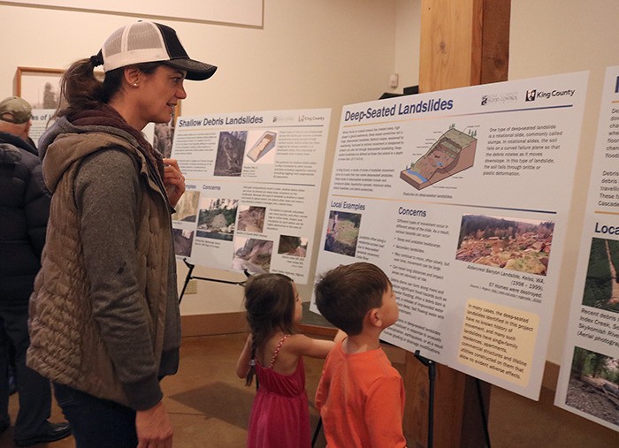 Alison Uno and her children Jasmine and Dylan read the information slides around the room about the different types of landslides seen in King County.