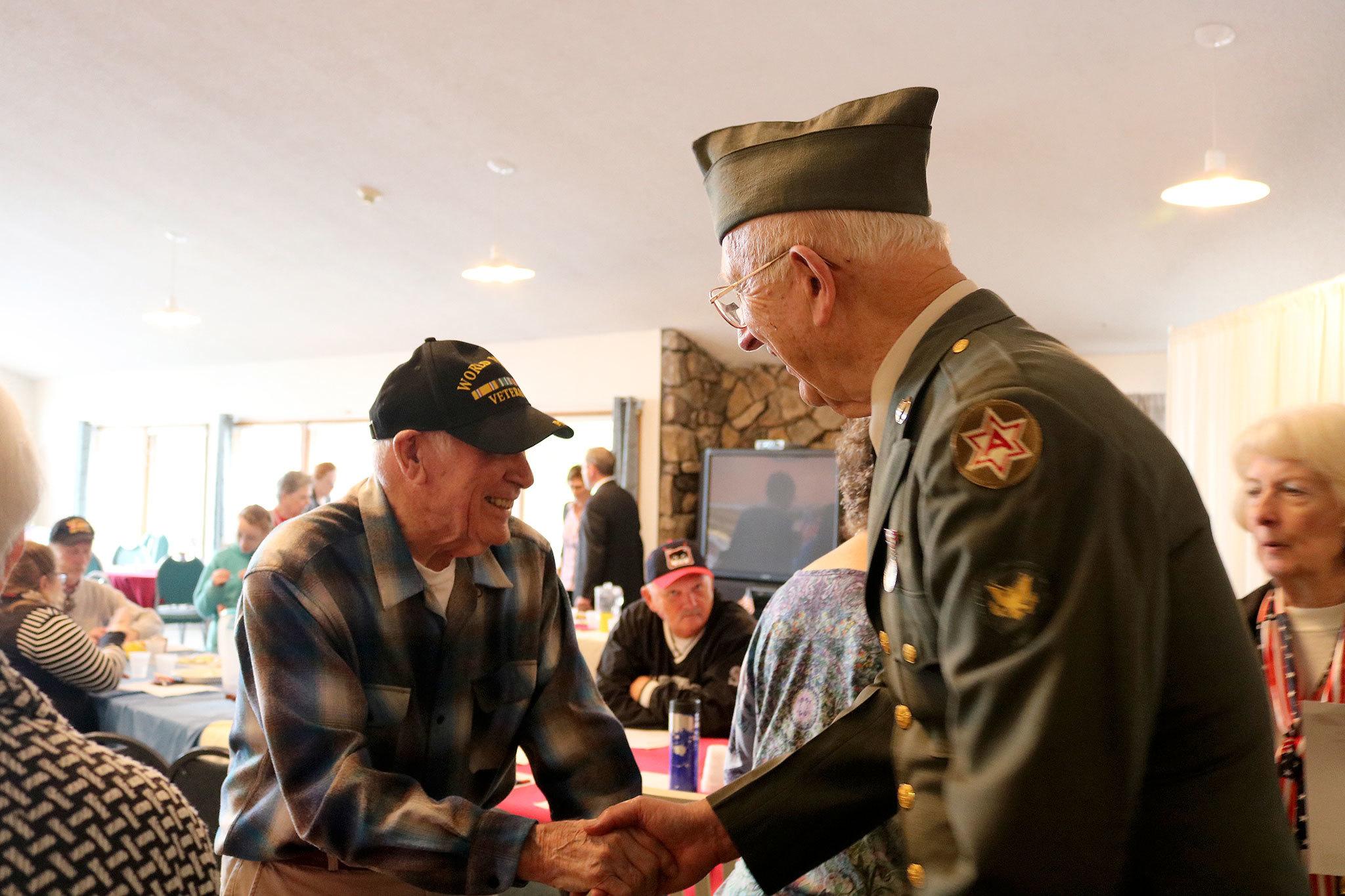 Bob Hamerly and Harley Brumbaugh shake hands at the Mount Si Senior Center after not having seen each other in some time. (Evan Pappas/Staff Photo)