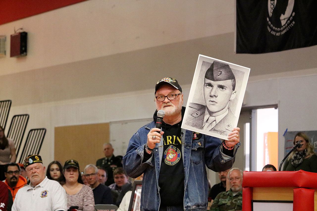 Artist and founder of the Fallen Heroes Project, Michael Reagan, shows the audience of Mount Si High School students his portrait of Vincent Santaniello, a friend he lost during the Vietnam War and one of the inspirations for the project. (Evan Pappas/Staff Photo)