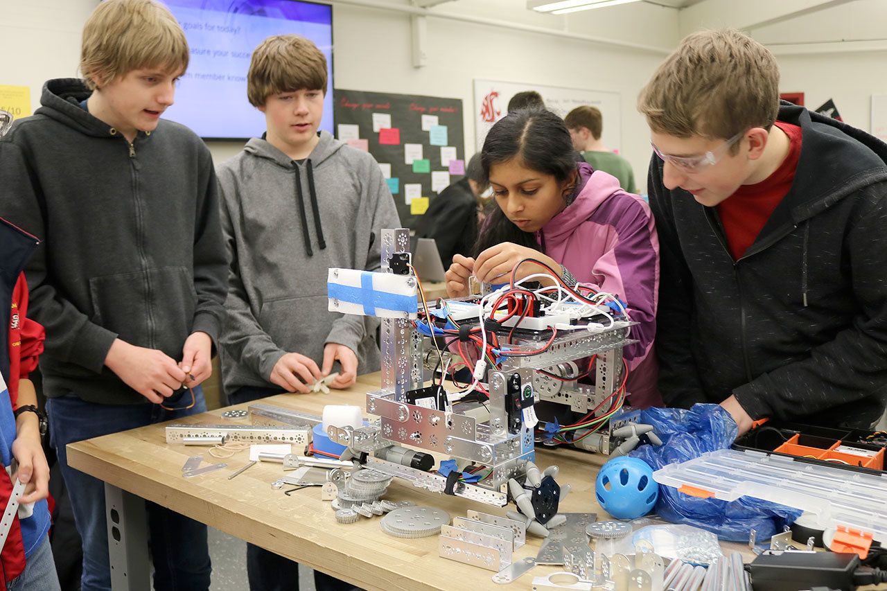 Hans Johnson, Davis Sauer, Shohini Ghosh and Peter Smith make small, last minute adjustments to their robot at the club meeting on Thursday, Dec. 8. (Evan Pappas/Staff Photo)