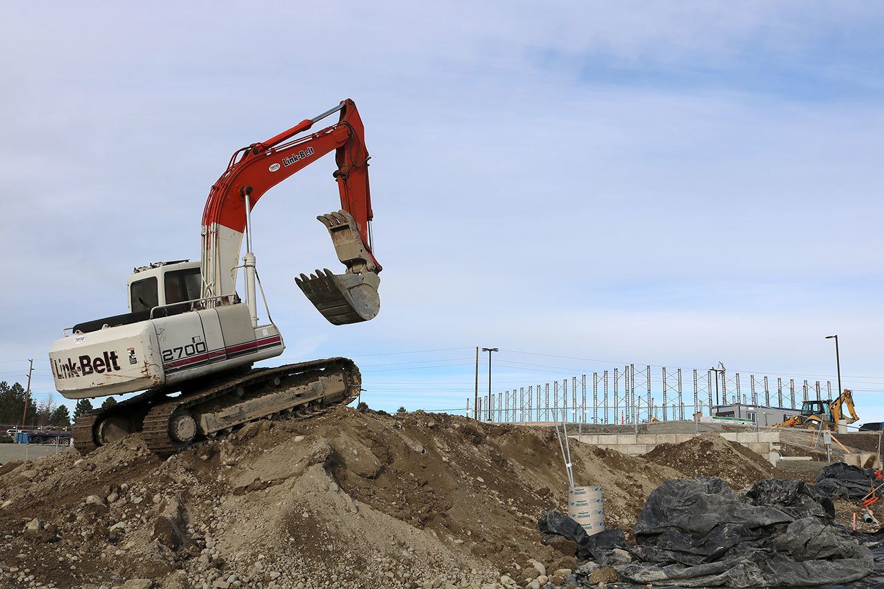 An excavator is driven up a mound of dirt on the site of the future Safeway store and Bartell Drugs complex, on Snoqualmie Parkway and S.E. Center Street. Both stores are targeting openings later this year. (Evan Pappas/Staff Photo)