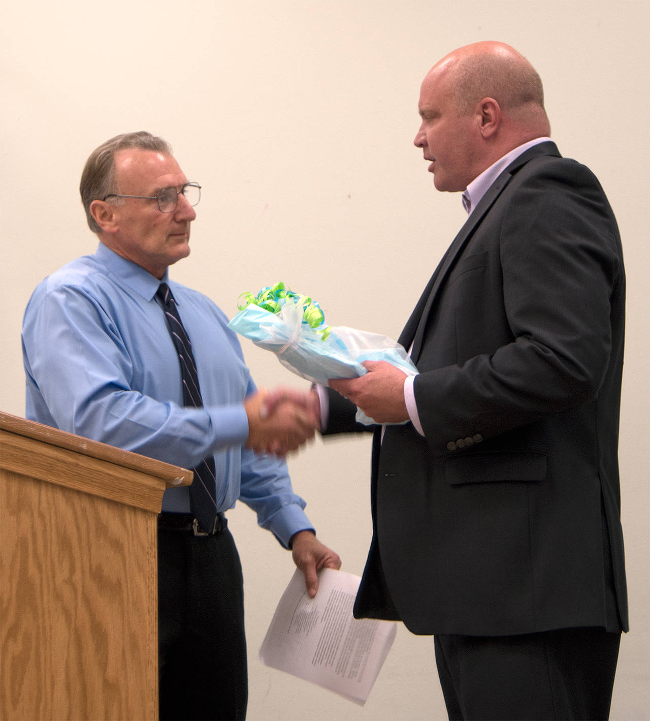 Carol Ladwig/Staff Photo                                Mayor pro tem Ross Loudenback, left, shakes McCulley’s hand at the North Bend City Council’s recognition of his retirement in June.