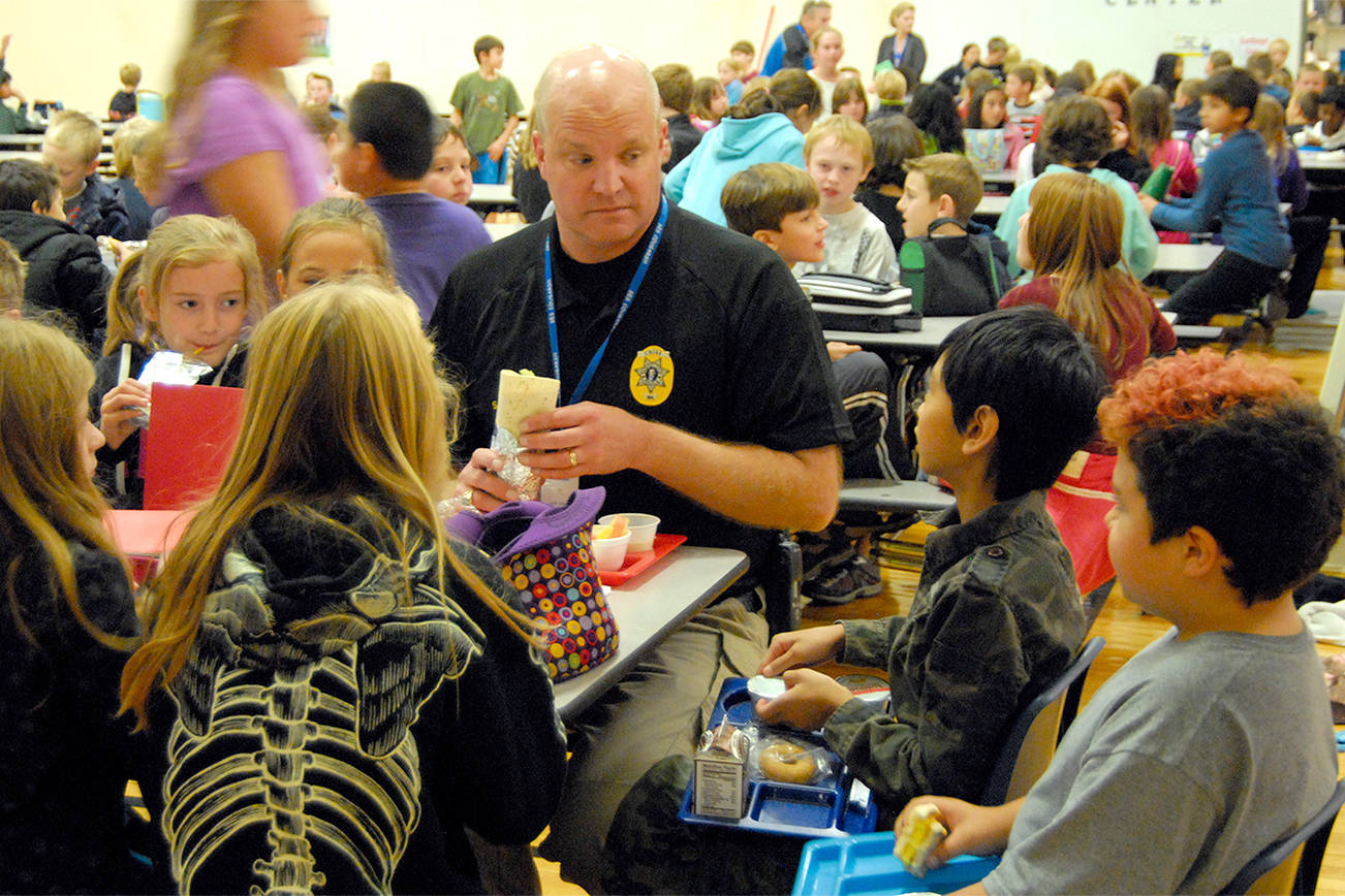 During a 2013 visit to North Bend Elementary School, students gather around to have lunch with Chief McCulley. Carol Ladwig/File Photo