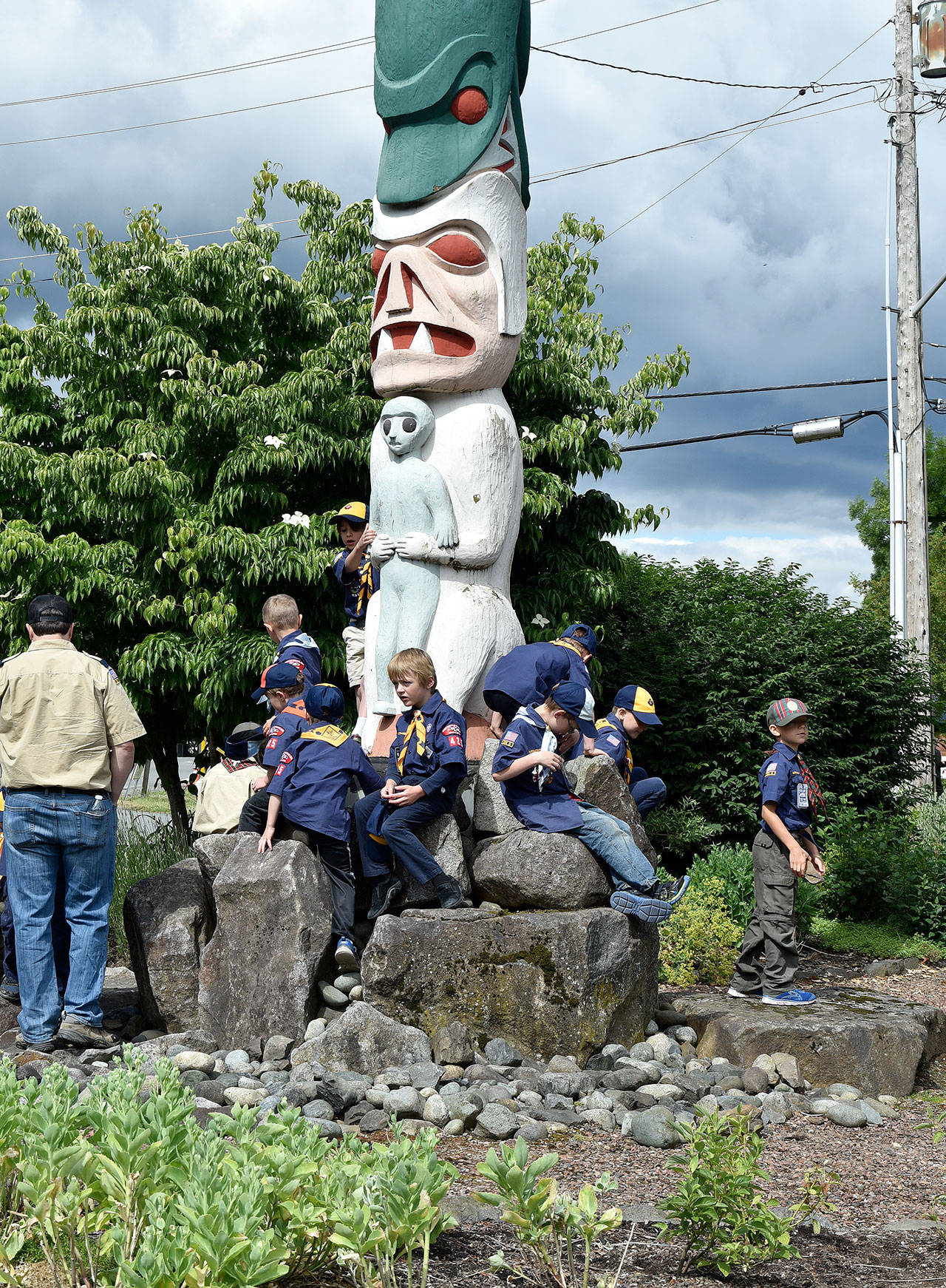 Boy Scouts from Troop 425 lounge on the Totem Garden totem pole as the floats line up for the Grand Parade Saturday.                                Carol Ladwig/Staff Photo