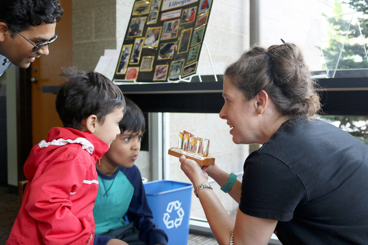 Mihit and Manas Mishra are shown a small exhibit detailing how baby salmon grow at Saturday’s summer reading kick-off event at the Snoqualmie Library.                                (Evan Pappas/Staff Photo)